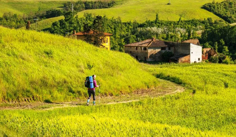 vrouwelijke wandelaar wandelt over toscaanse heuvels